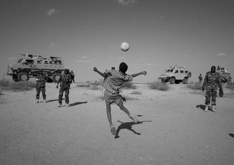 Child playing football with soldiers